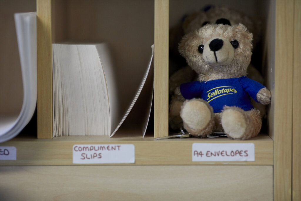 Paper slips and a teddy bear on a shelf.