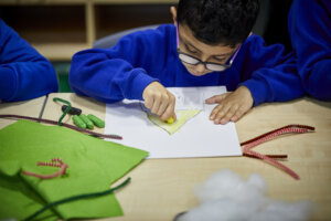 A schoolboy colouring a yellow triangle.