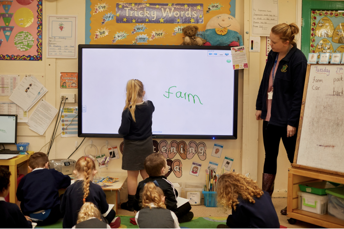 Child using an interactive white board in front of the class