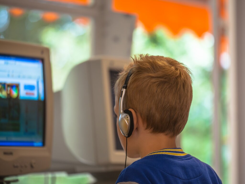 A boy with headphones at the computer.