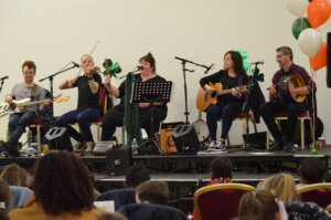 Musicians performing on stage with the guitar, the fiddle and the flute.