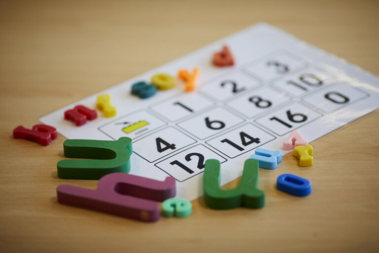 A printed worksheet with numbers on a desk, surrounded by plastic letters.