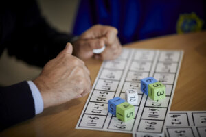 Hands on a desk, beside numeracy classwork and dice.