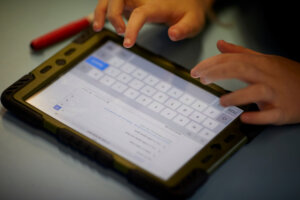 A child typing on a tablet.