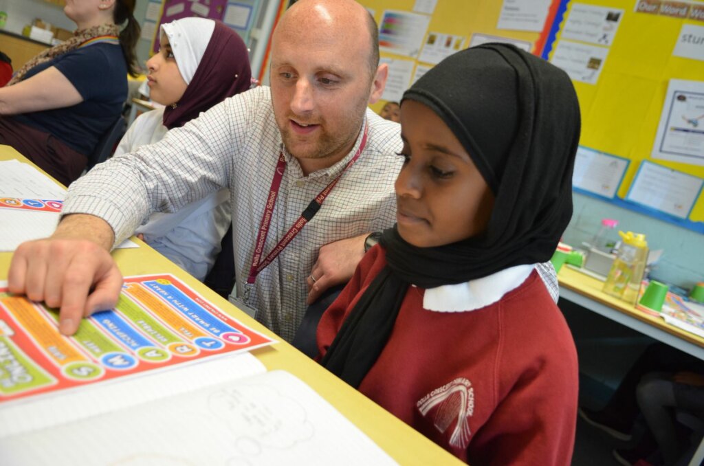 A teacher helping a girl in the classroom.