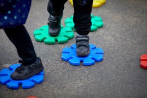 A child's feet stepping on colourful, plastic stepping stones in the playground.