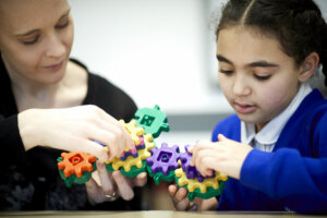 A teacher and pupil playing with a toy.