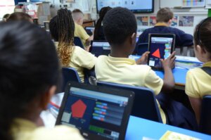 Pupils sitting in the classroom, working on tablets.