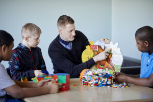 A teacher and three boys sitting around a table, looking at a picture book.