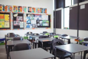 An empty classroom with chairs and desks standing in rows.