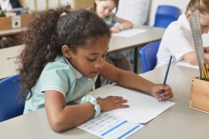 A girl writing at her desk in the classroom.