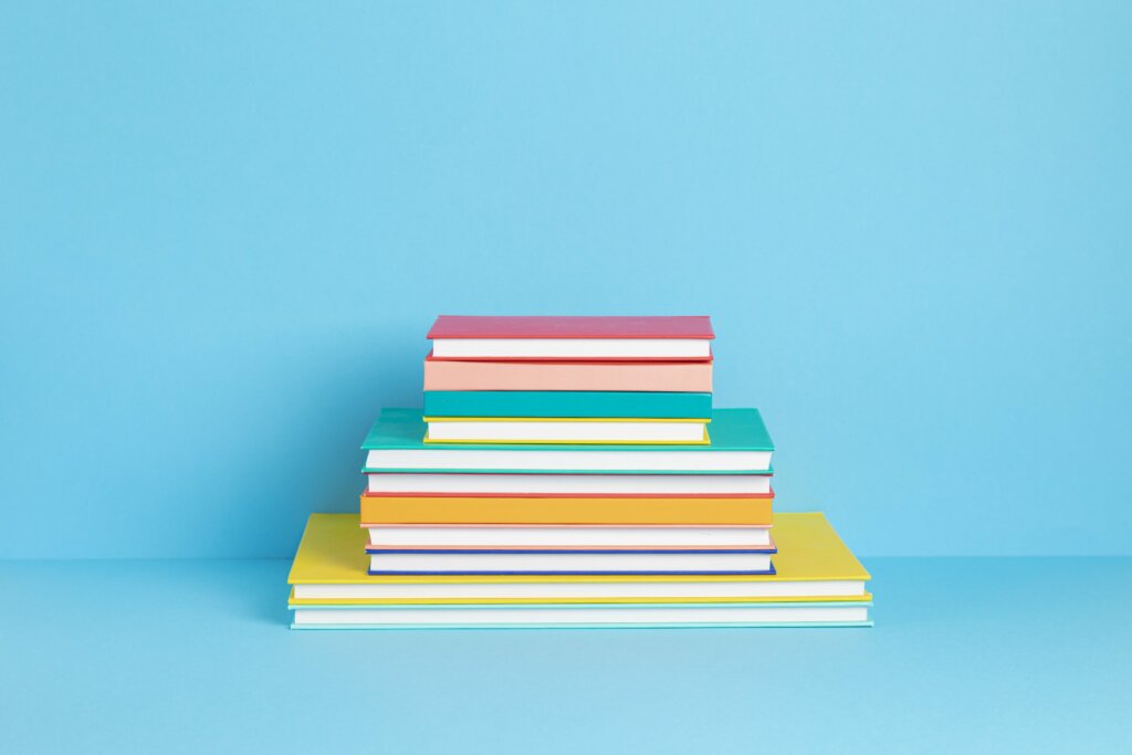 A stack of colourful books with a blue background.