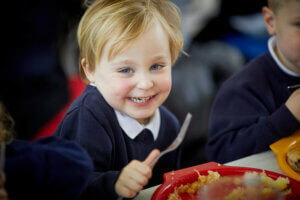 A young boy enjoying his school dinner.