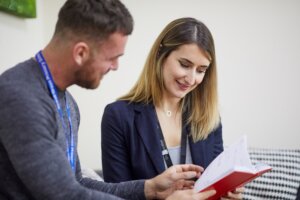 A man and woman looking through a work book together.