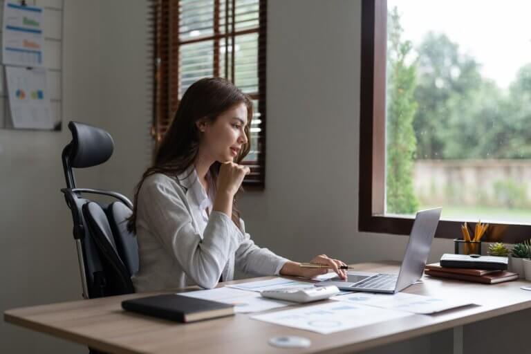 Staff member sits at a desk, using a laptop in the office